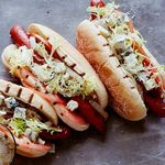 Hotdogs mit Rinderwürstchen, Gorgonzola, Tomaten, Zwiebeln und Friséesalat