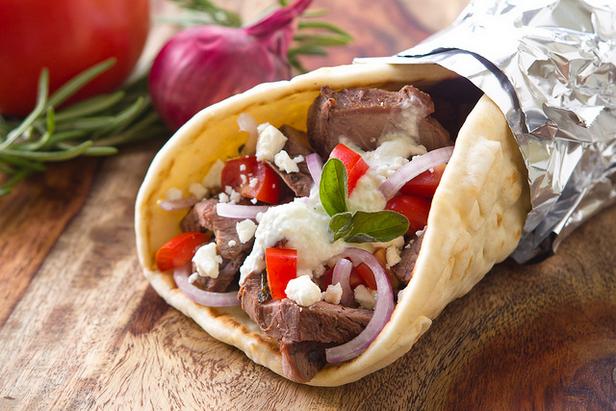 Zubereitung von griechischen Gyros: Mit Lammfleisch gefülltes Fladenbrot mit Tzatziki-Sauce