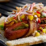 Hotdog mit in Speck gewickelter Wurst und Ananas-Topping