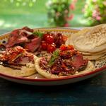 Lamm-Pita mit Granatapfelglasur und Minze am Spieß, gegrillte Tomaten und griechischer Krautsalat