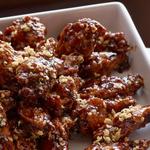 Frittierte Hähnchenflügel in klebriger Glasur mit knusprigen Zwiebeln