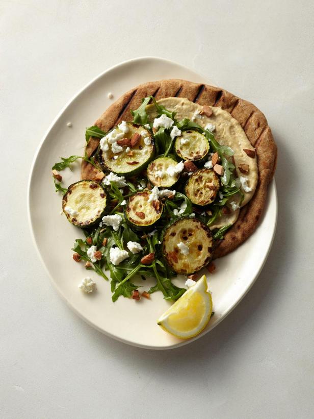 Fladenbrot mit gebackenen Zucchini, Hummus, Rucola, Ziegenkäse und Mandeln