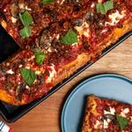 Pizza mit Wurst und Champignons auf einem Backblech